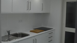 A modern kitchen with white cabinets, a stainless steel sink, and a wooden cutting board.