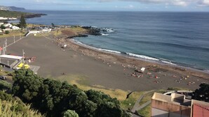 A beach with a wide sandy area, a rocky shoreline, and a clear view of the sea.