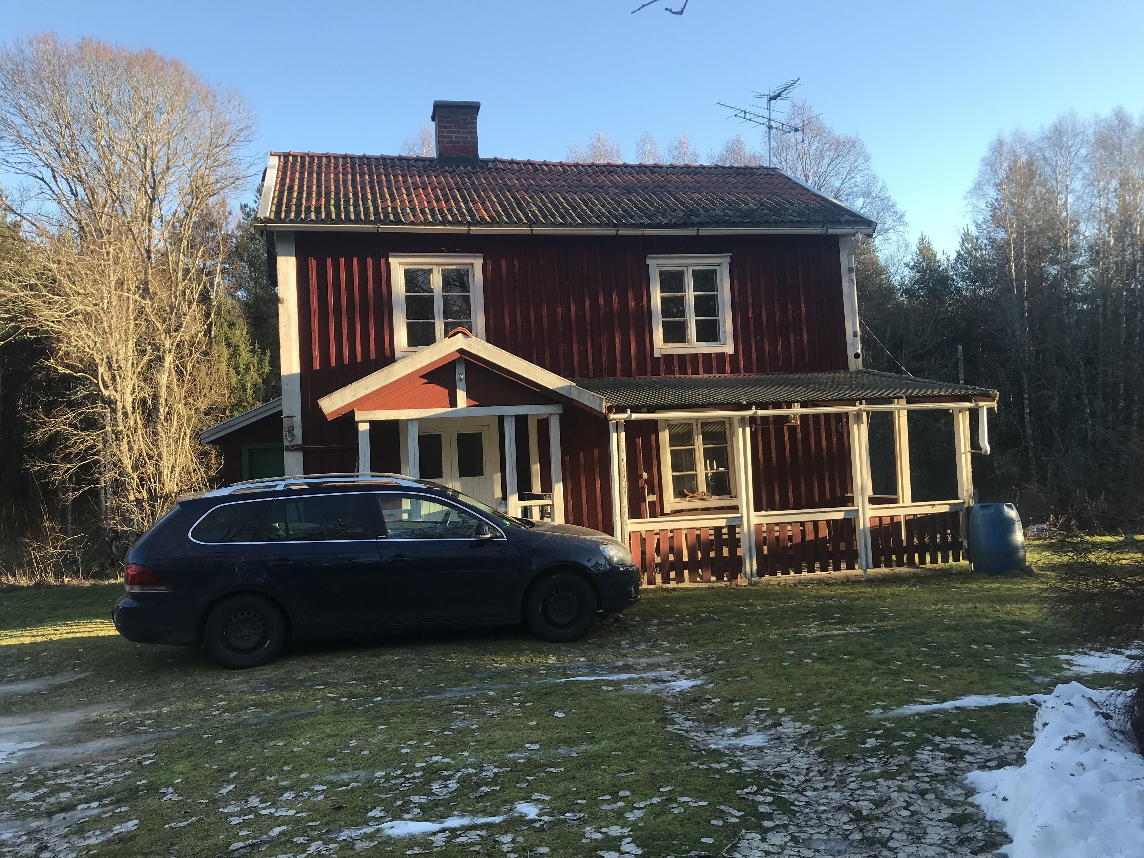 A two-story house with a porch and a car parked in front.