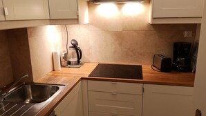 Eine kleine Küche mit Spüle, Herd und Kaffeemaschine.