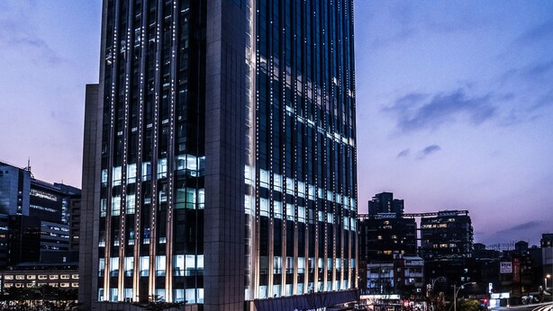A modern high-rise building with a prominent glass facade, a well-lit entrance, and a surrounding urban environment. - The Place Taipei (Taipei)