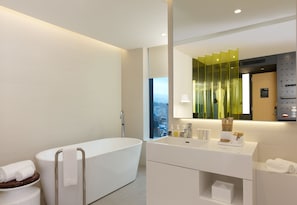 A modern bathroom with a freestanding bathtub, a vanity with a mirror, and a window offering a city view.