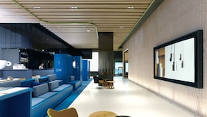 A modern lobby with a blue seating area, a reception desk, and a large mirror on the wall. - The Place Taipei (Taipei)
