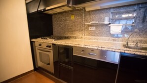 Une cuisine dotée d’un plan de travail en granit, d’appareils électroménagers en acier inoxydable et d’un four encastré.