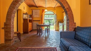 A cozy interior with a brick archway, a dining area with a table and chairs, and a blue sofa.