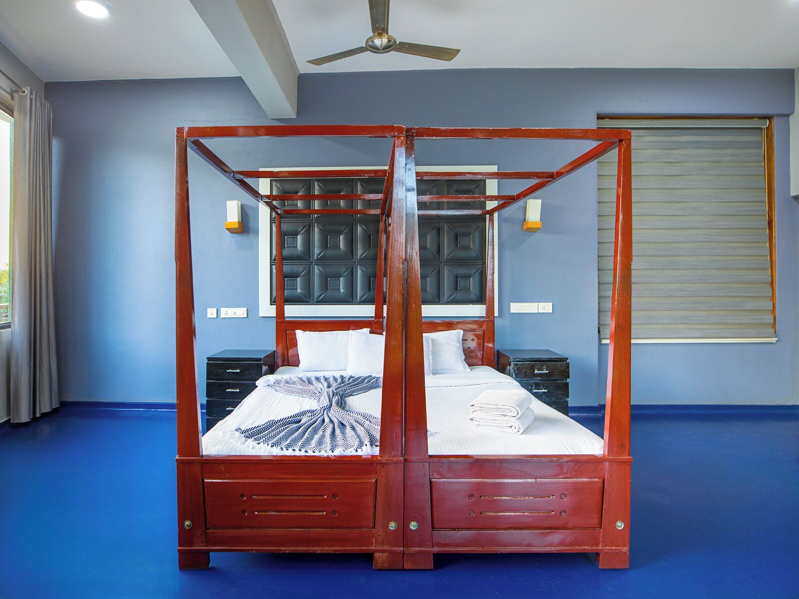 Una cama con dosel, un cabecero, dos mesitas de noche y un ventilador de techo.