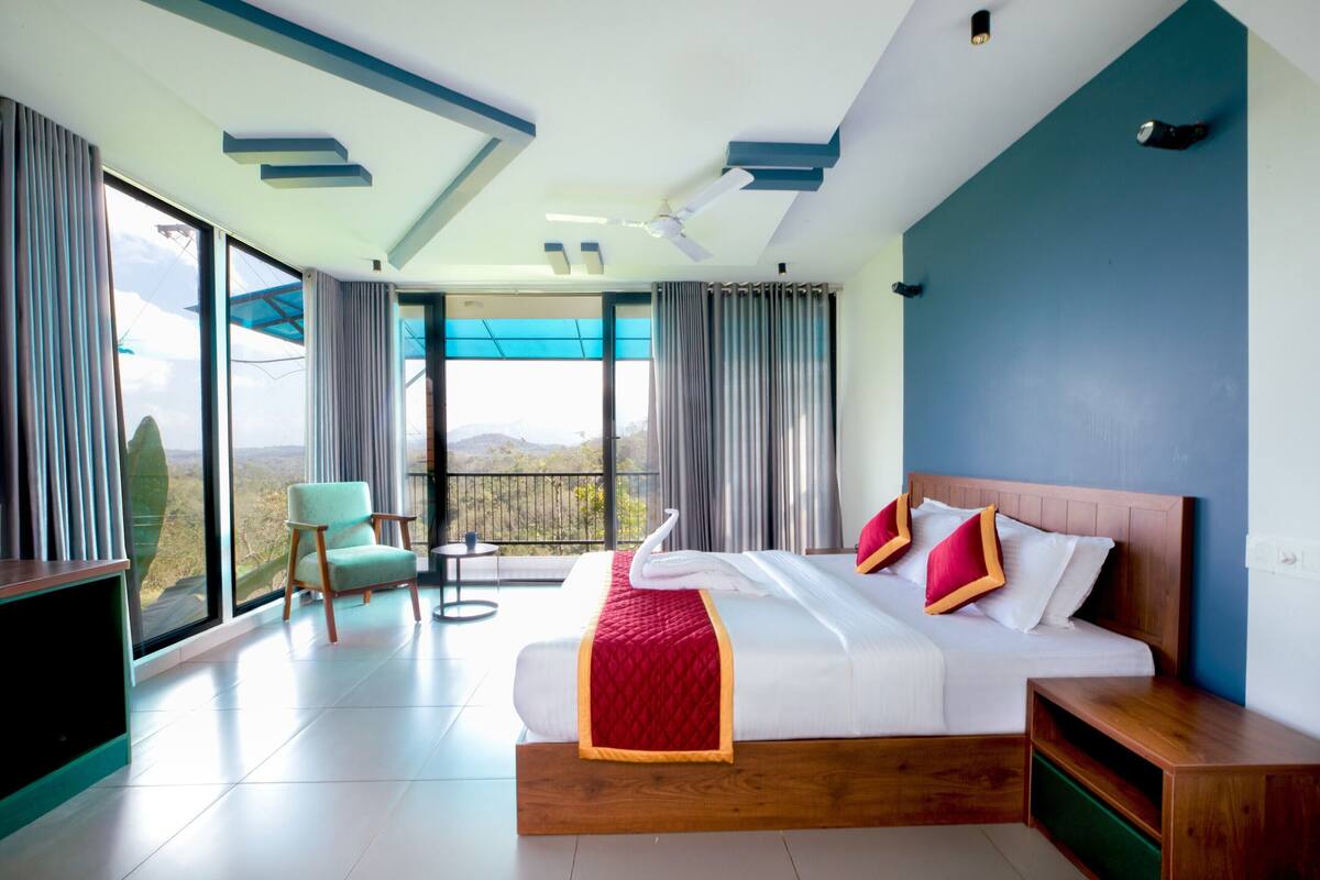Una habitación de hotel moderna con una cama grande, un balcón con vistas y un ventilador de techo.