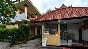 A bungalow with a tiled roof, a motorcycle parked outside, and a signboard. - Mega Cahya Bungalow (Lembongan Island)