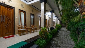 A hotel corridor with wooden doors, a tiled floor, and a green mat. - Mega Cahya Bungalow (Lembongan Island)