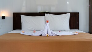 A neatly made bed with a brown bedspread and white pillows. - Mega Cahya Bungalow (Lembongan Island)