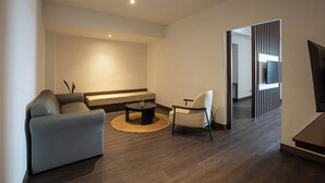 A modern living room with a sofa, armchair, coffee table, and a flat-screen TV. - Wiltop Hotel (Jambi)