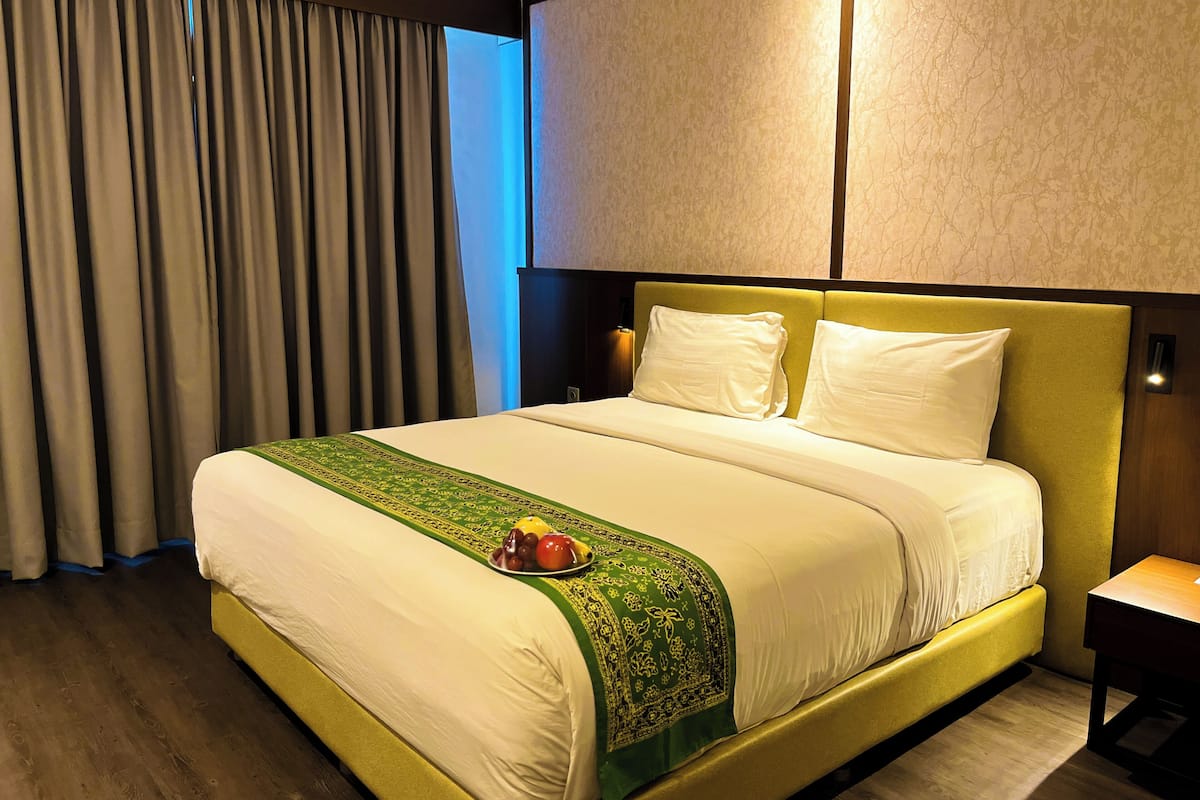 A hotel room with a bed, a nightstand, a lamp, a window with curtains, and a wall with a textured pattern.