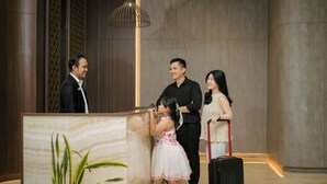 A reception desk with a marble counter, a potted plant, and a modern pendant light. - Wiltop Hotel (Jambi)