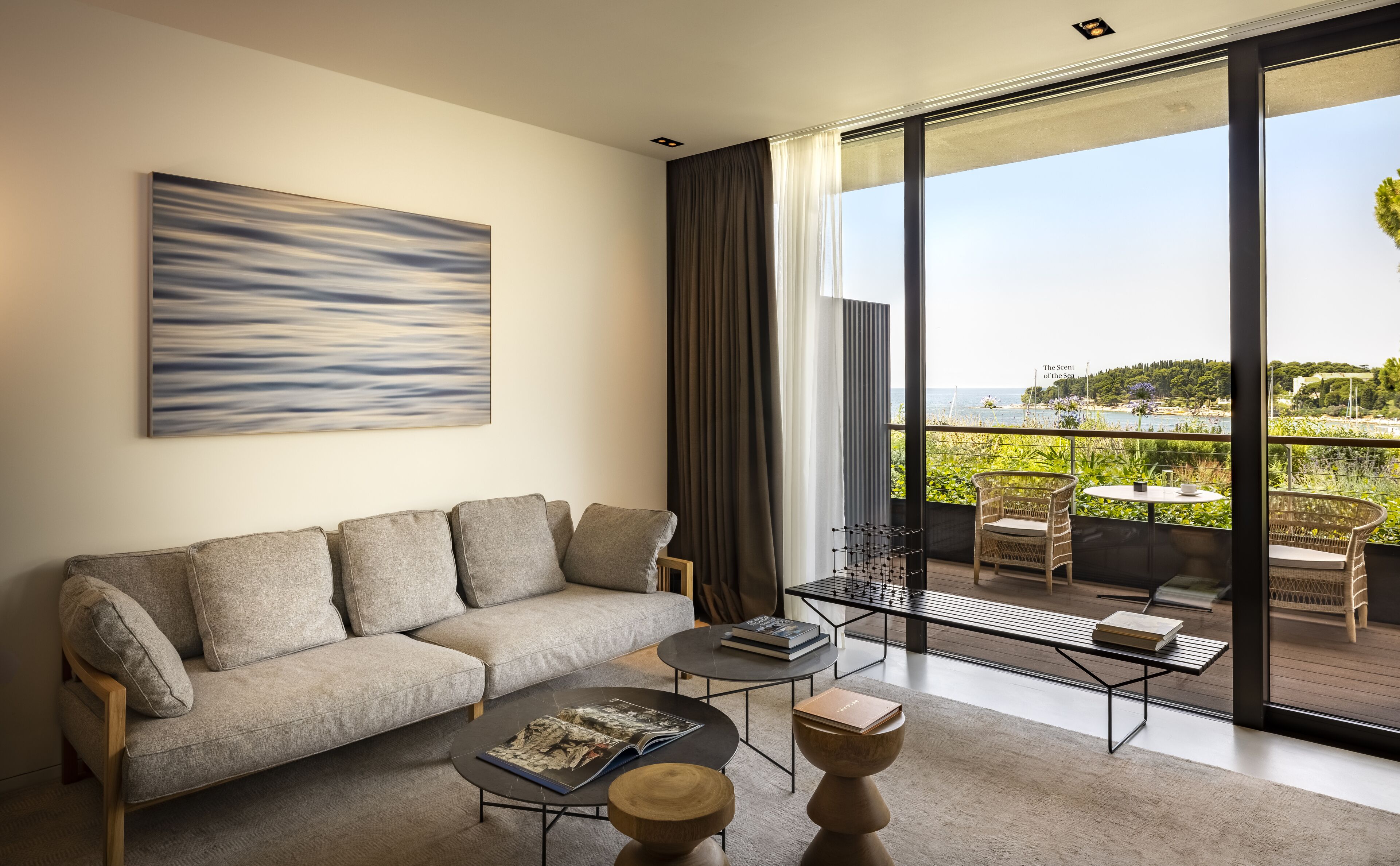 Una sala de estar moderna con un sofá, una mesa de centro y vistas al mar a través de amplios ventanales.