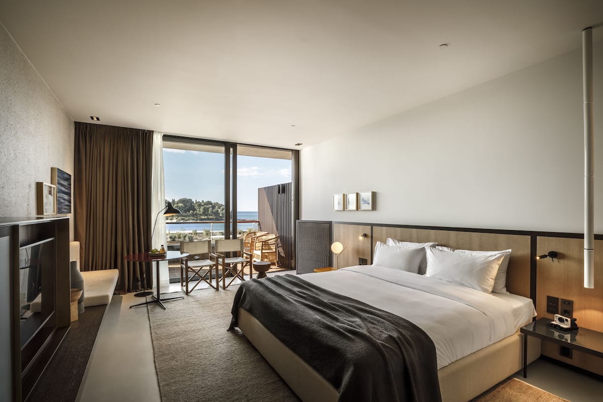 Una habitación de hotel moderna con una cama grande, un escritorio y vistas al exterior.