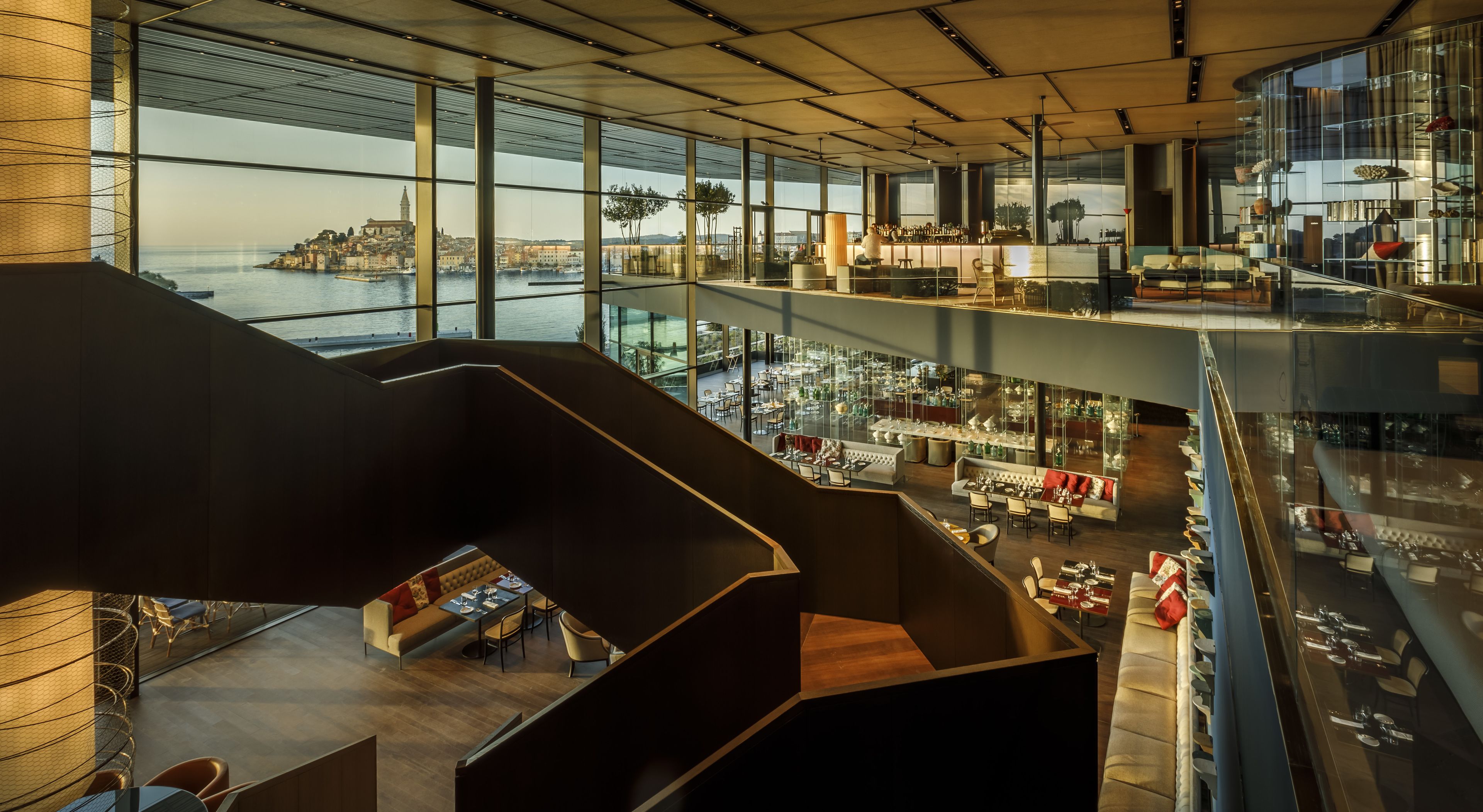 A multi-level interior with a view of a waterfront cityscape.