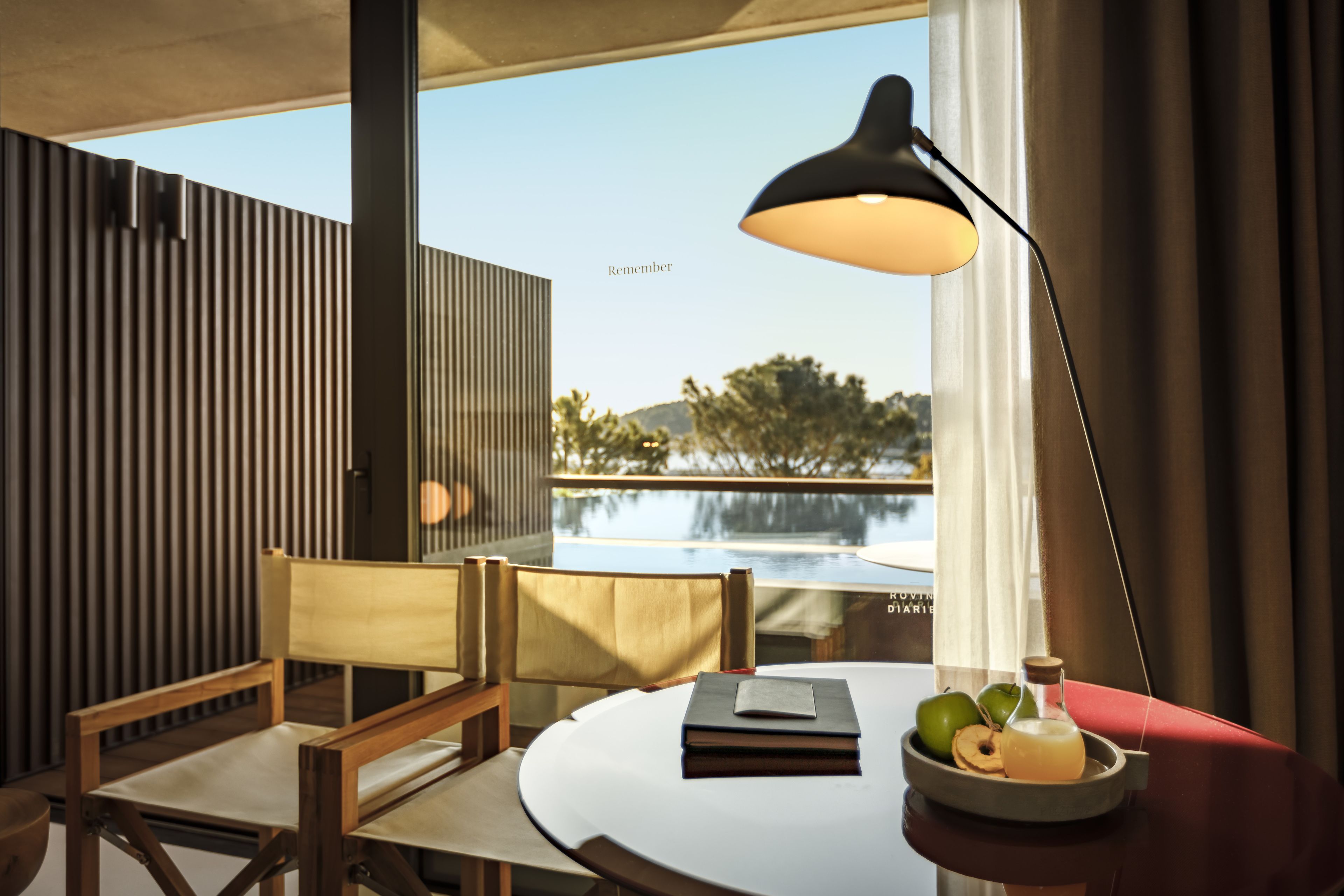A modern room with a round table, a lamp, and a view of a pool.