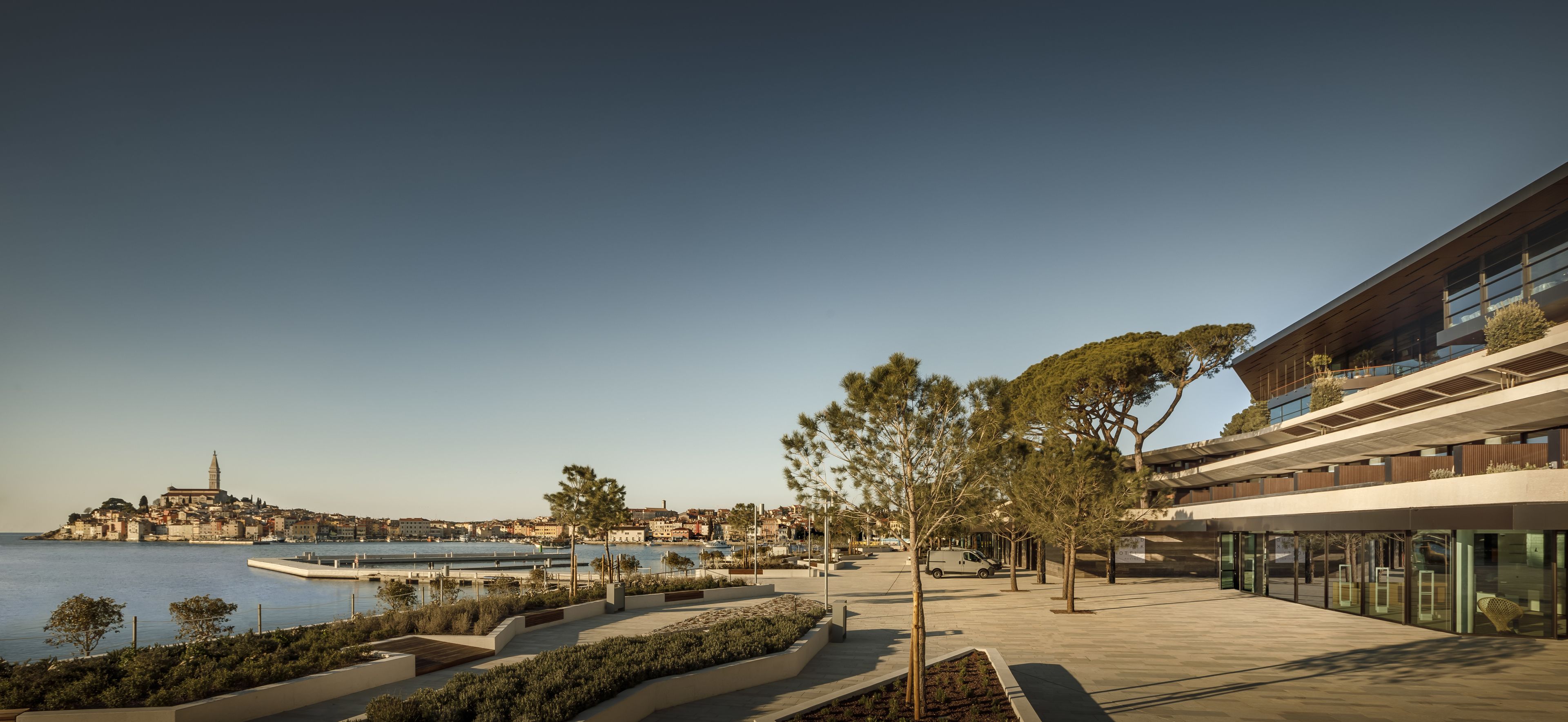 Una passeggiata lungomare con un edificio moderno caratterizzato da ampie vetrate e un tetto piatto.