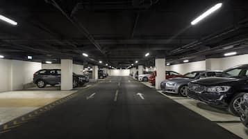 Un estacionamiento subterráneo de varios niveles con varios coches aparcados en plazas designadas.