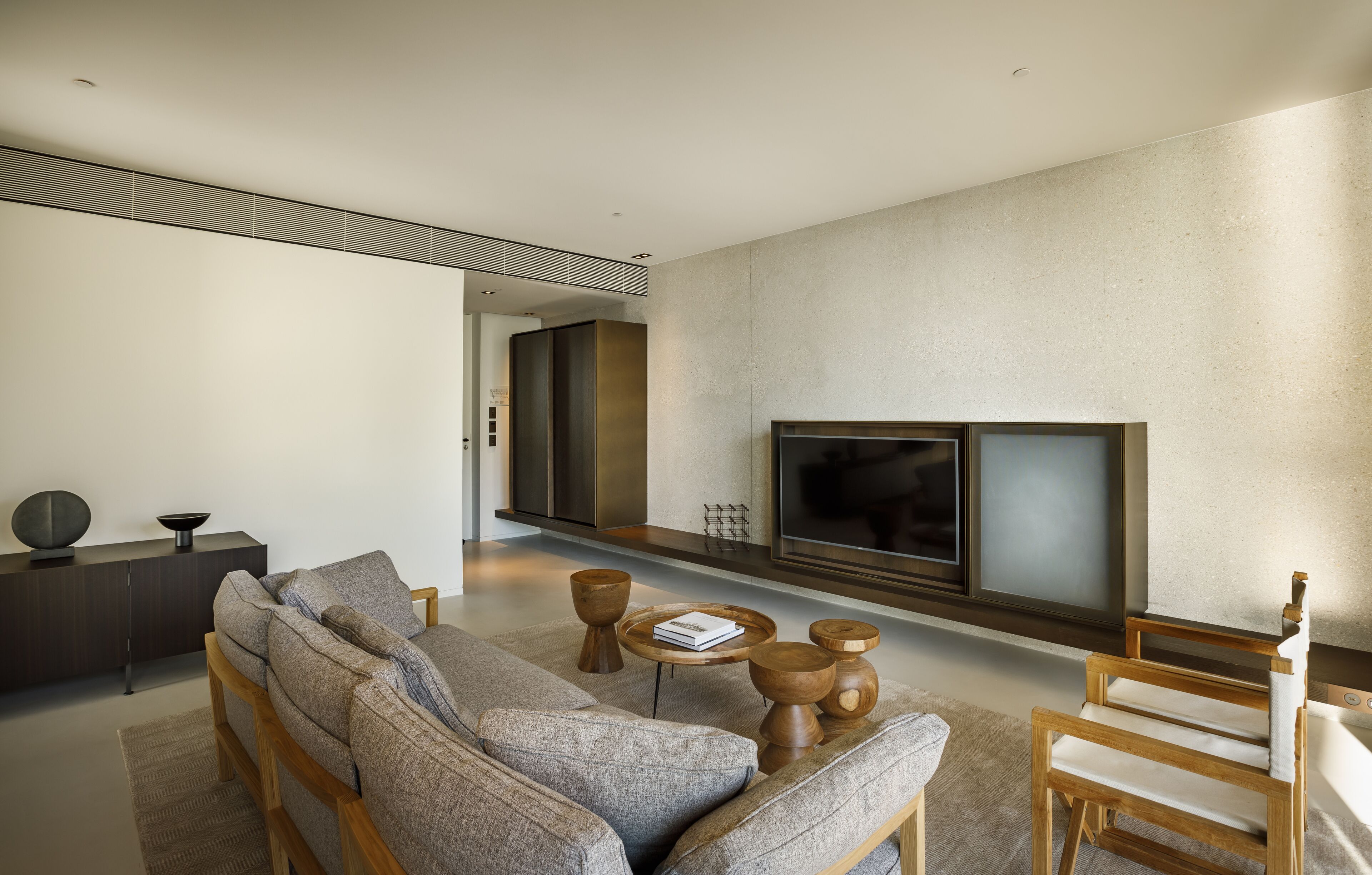 A modern living room with a sectional sofa, a wooden coffee table, and a flat-screen TV mounted on the wall.