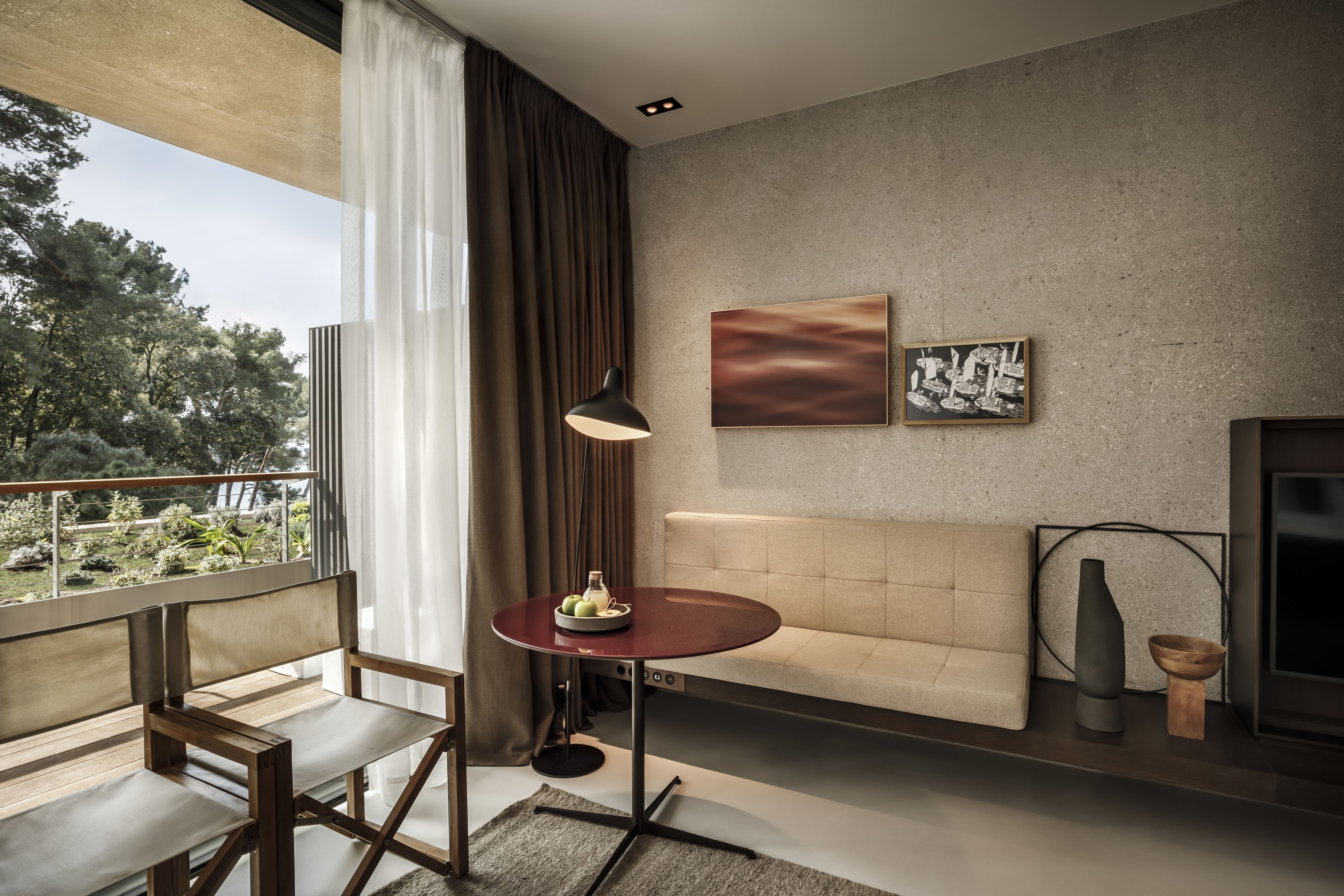 A modern living room with a sofa, a round table with a vase, and artwork on the wall.