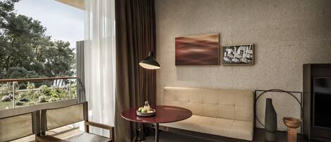 A modern living room with a sofa, a round table with a vase, and artwork on the wall.
