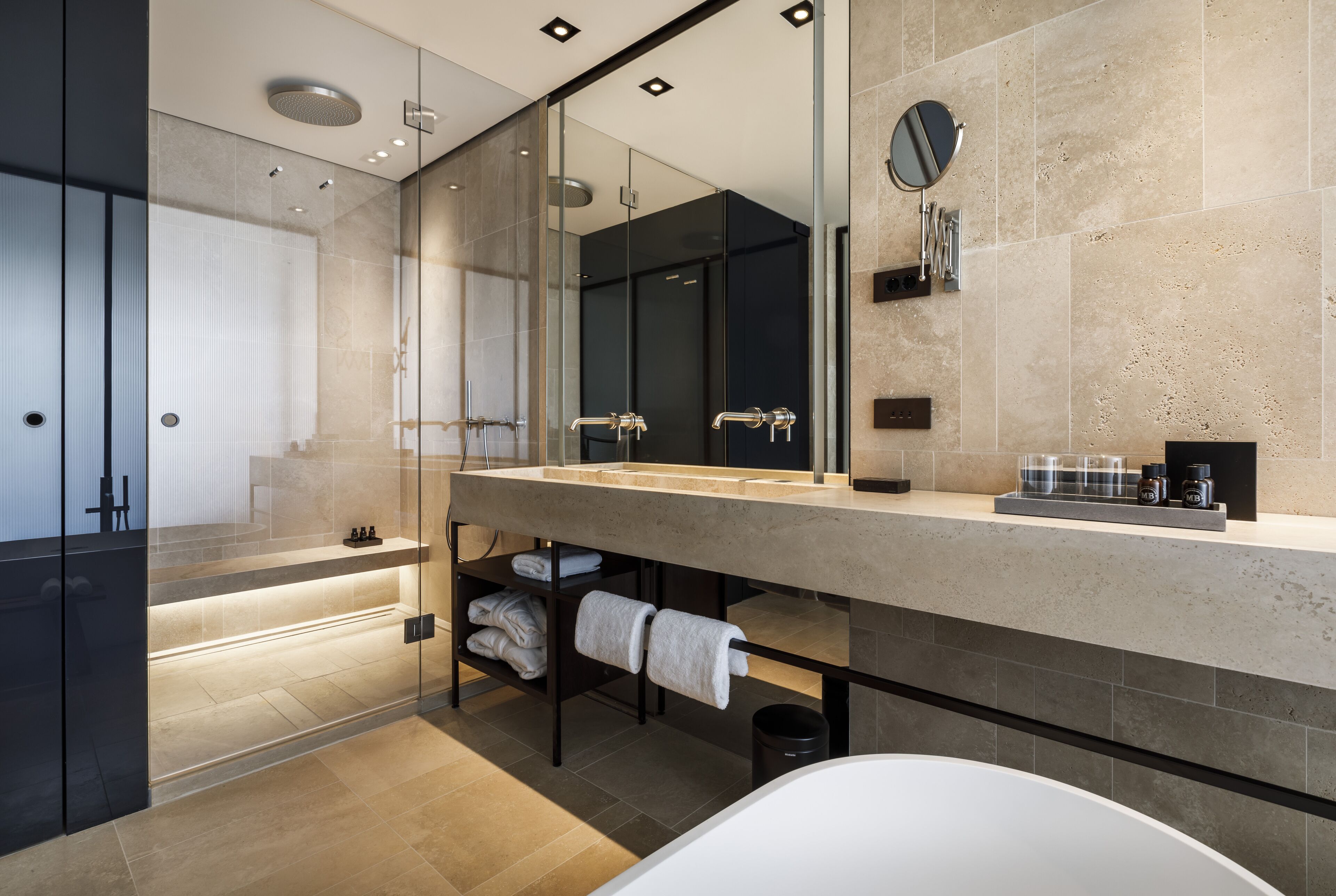 A modern bathroom with a large mirror, a bathtub, and a shower area.