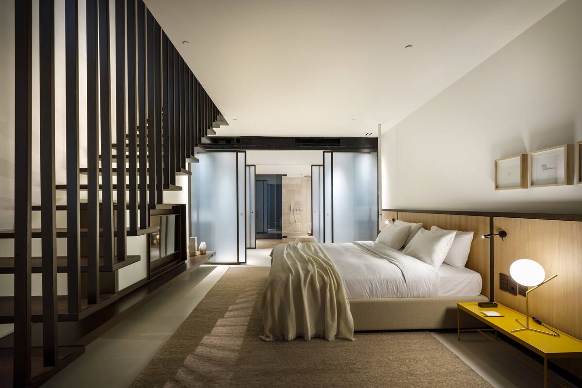 Un dormitorio moderno con cama, mesita de noche y lámpara.