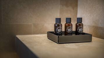 Three bottles of MB body wash, conditioner, and shampoo on a tray.