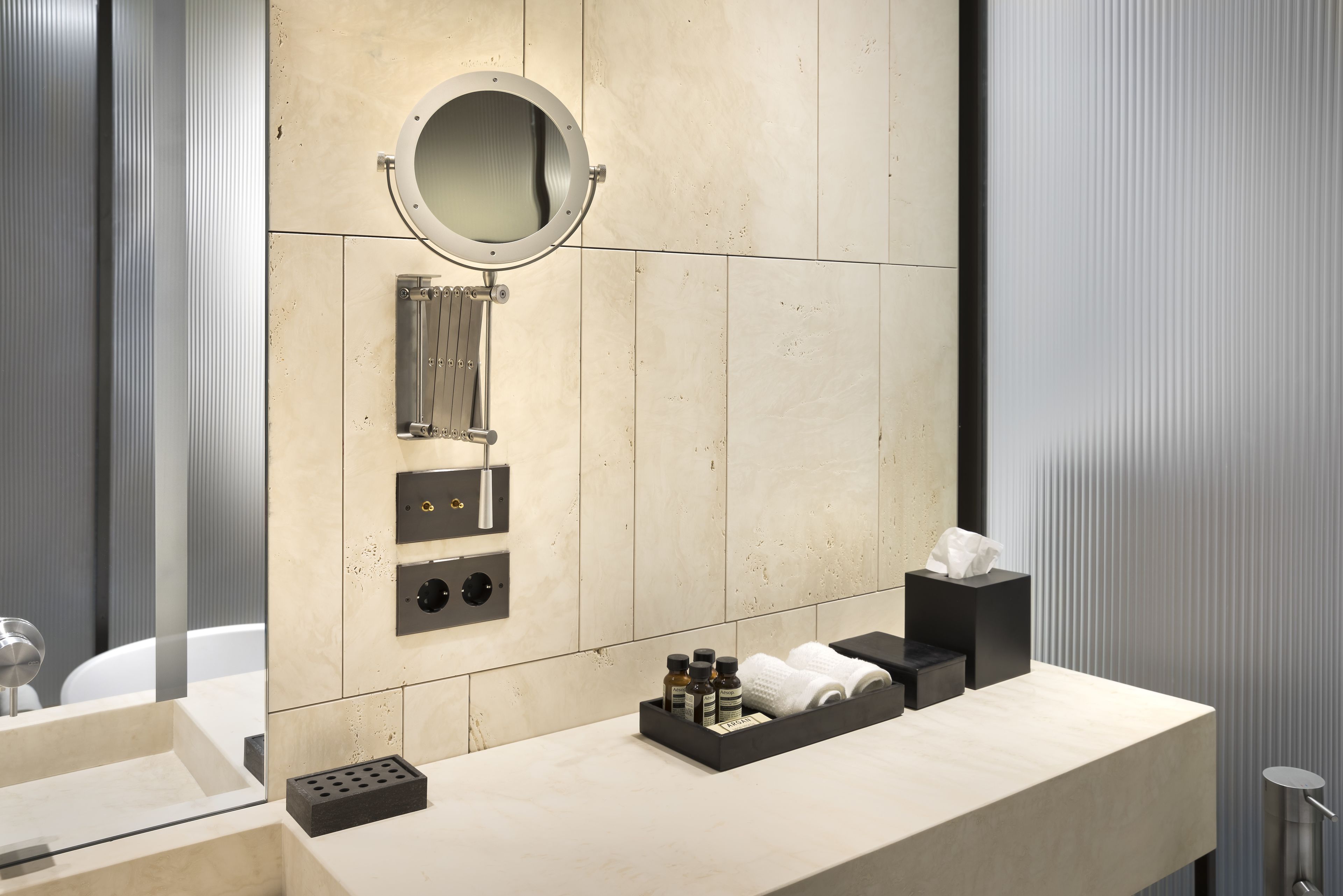 Un baño moderno con un espejo grande, un perchero para toallas y una bandeja con artículos de aseo.