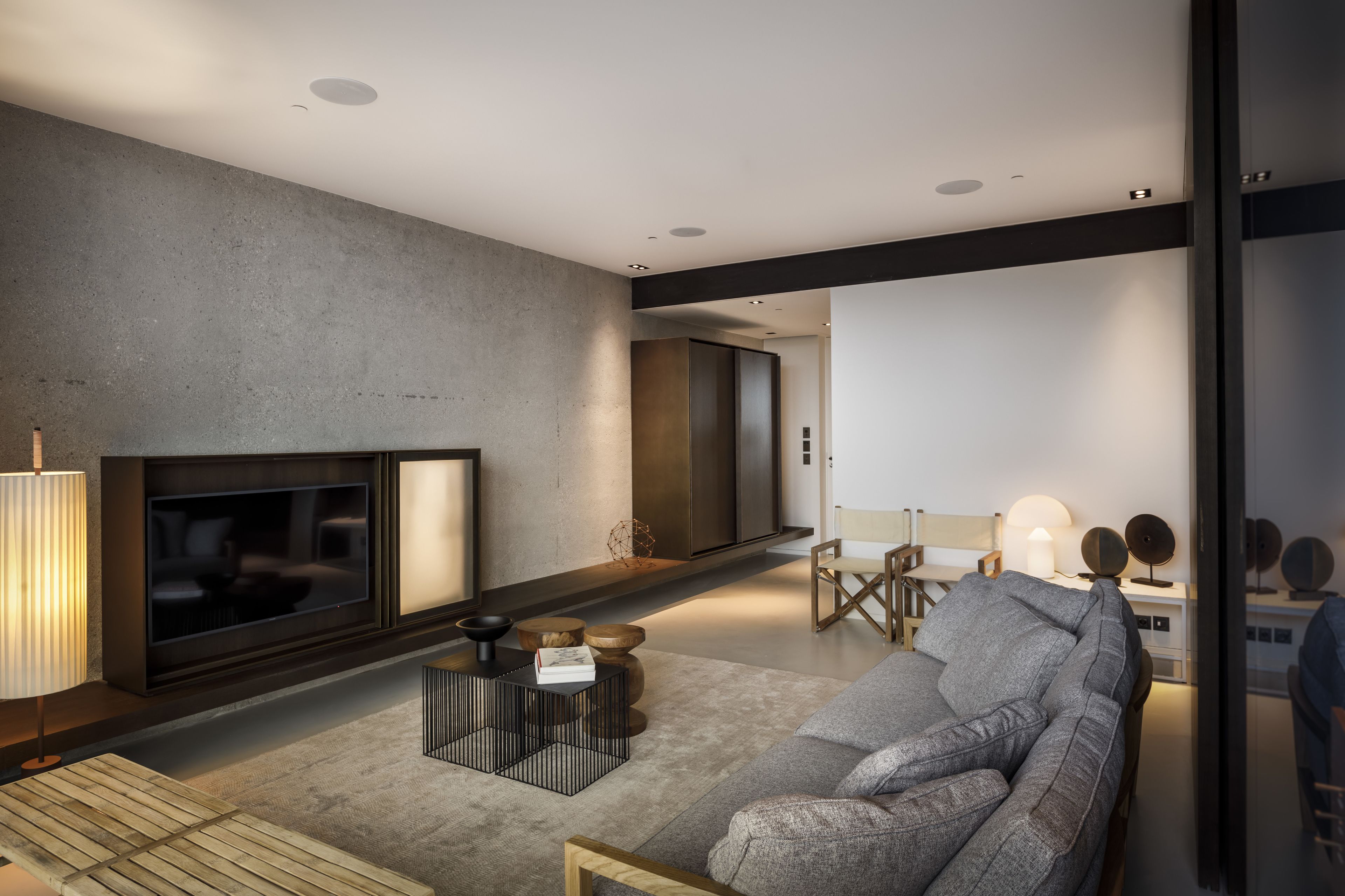 Un salon moderne avec un téléviseur à écran plat, un canapé, une table basse et une lampe.