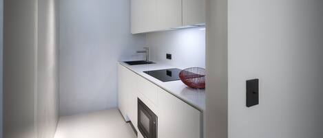 A modern kitchen with white cabinetry, a black countertop, and a red bowl.