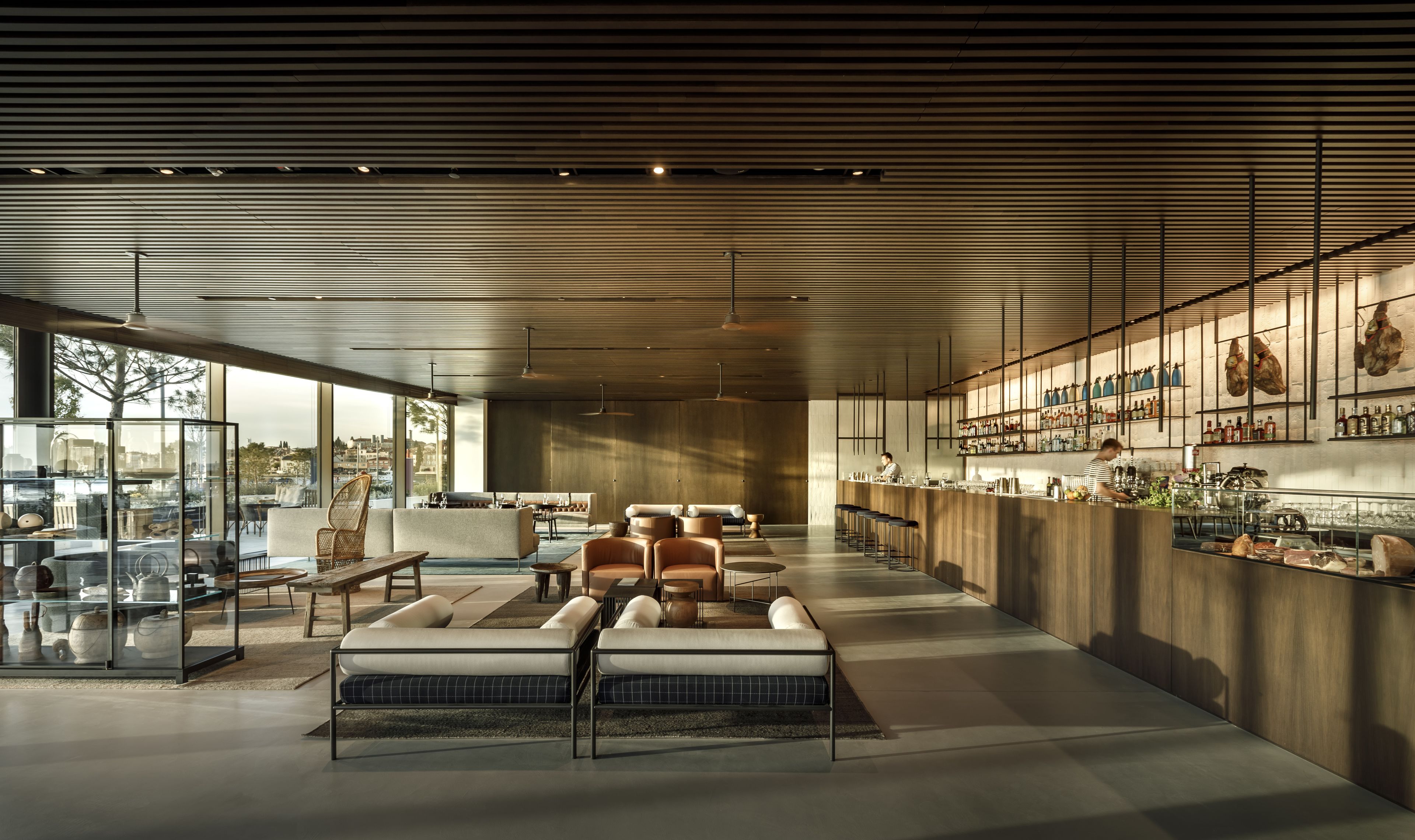 A spacious, modern lounge area with a bar, seating arrangements, and large windows offering views of the city.