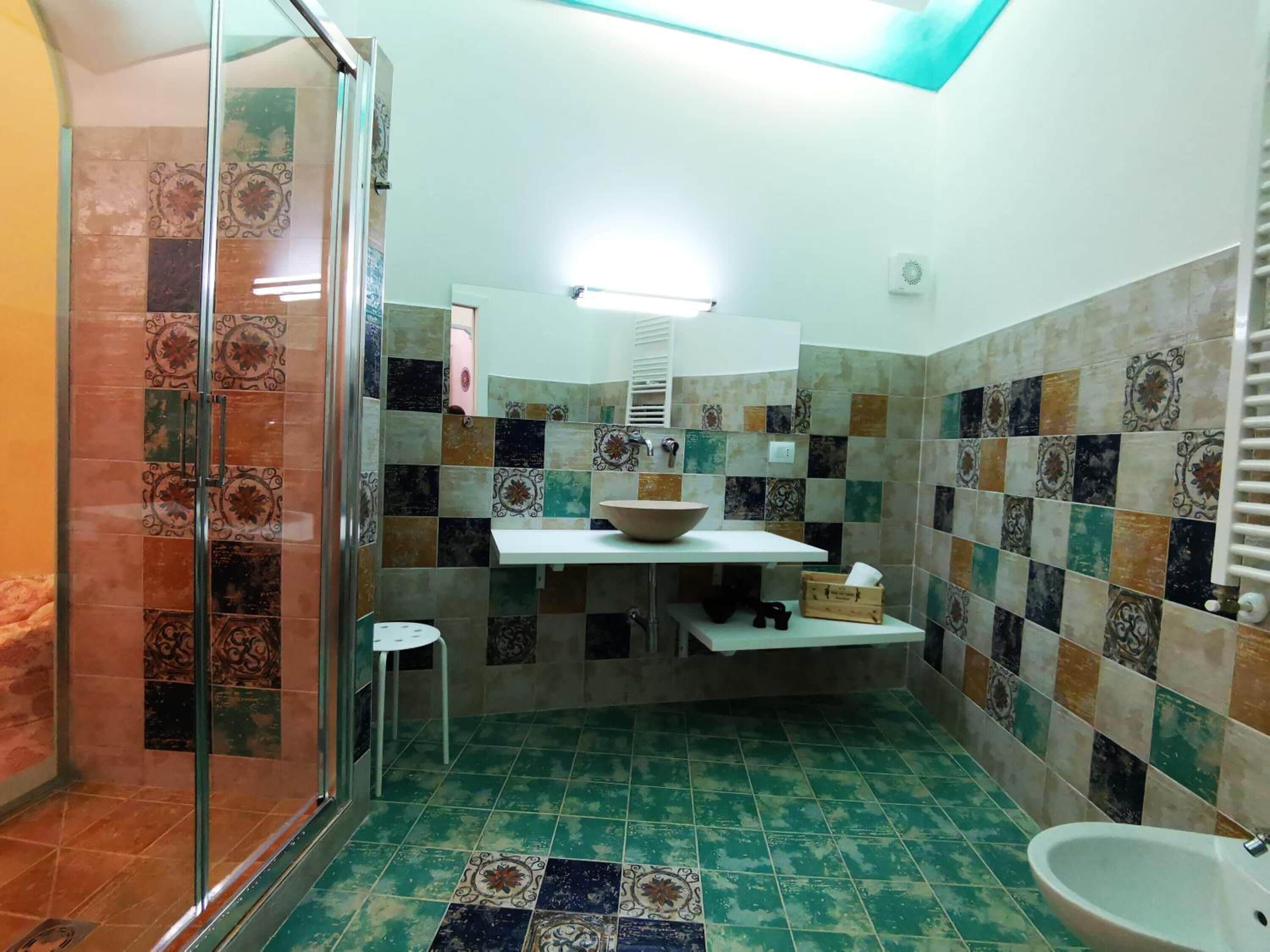 Une salle de bain avec une douche à parois de verre, un lavabo en forme de cuvette et des toilettes.