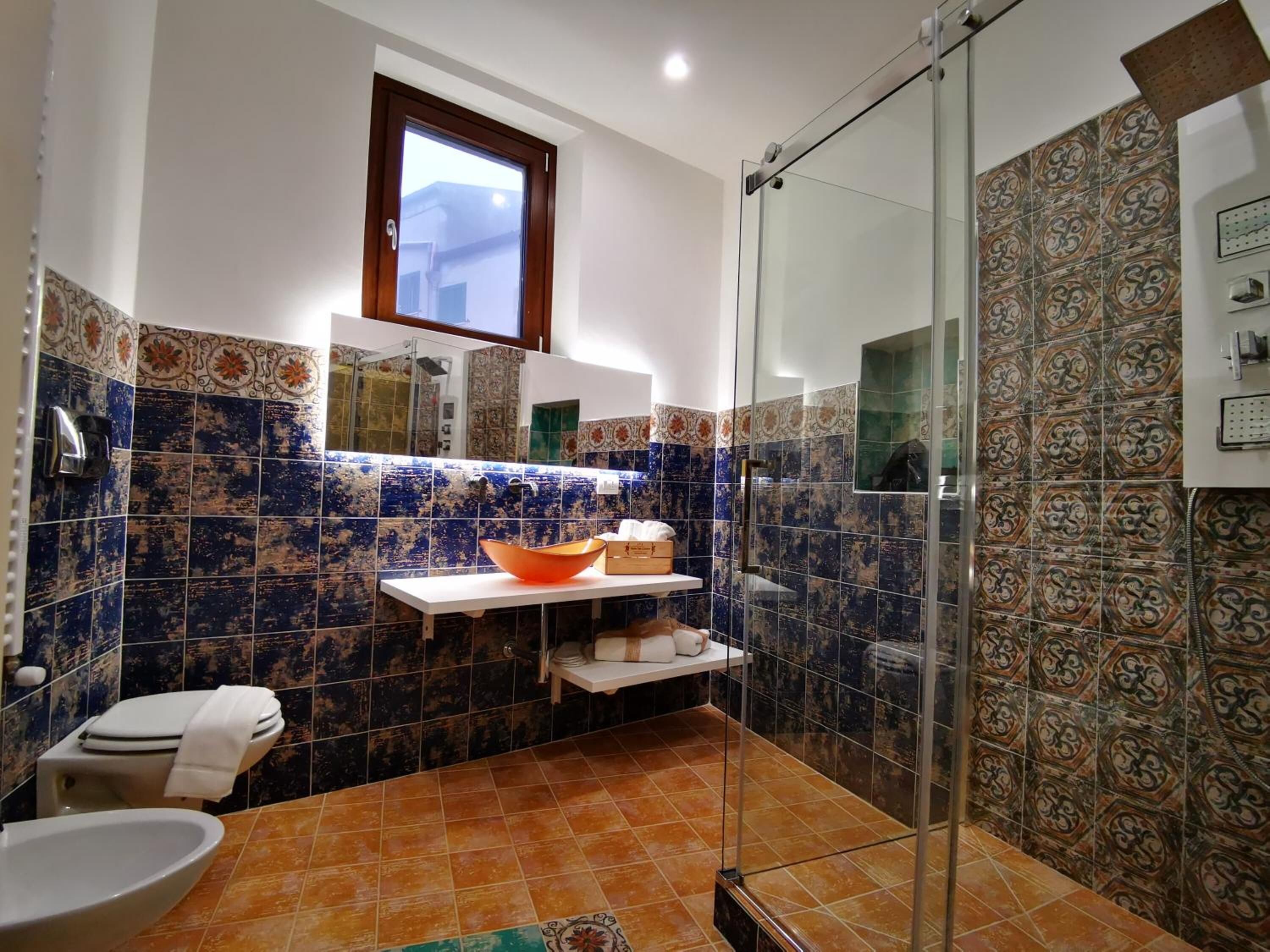 Un baño con cabina de ducha de vidrio, un lavabo blanco y un inodoro.