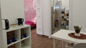 Une chambre moderne avec une table blanche, une cabine de douche en verre, un mur rose et un plancher en bois.