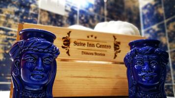 Dos jarrones azules de cerámica con diseños intrincados, situados frente a una caja de madera con la etiqueta "Suite Inn Centro Dimora Stories".