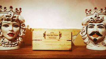 Two ceramic figurines with crowns on a shelf, a wooden box labeled "Suite Inn Centro," and a partial view of a wall.