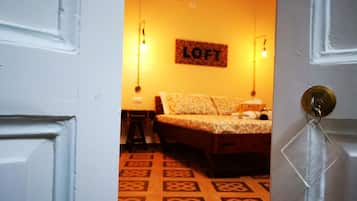 A room with a bed, a wall-mounted sign reading "LOFT", and a patterned floor.