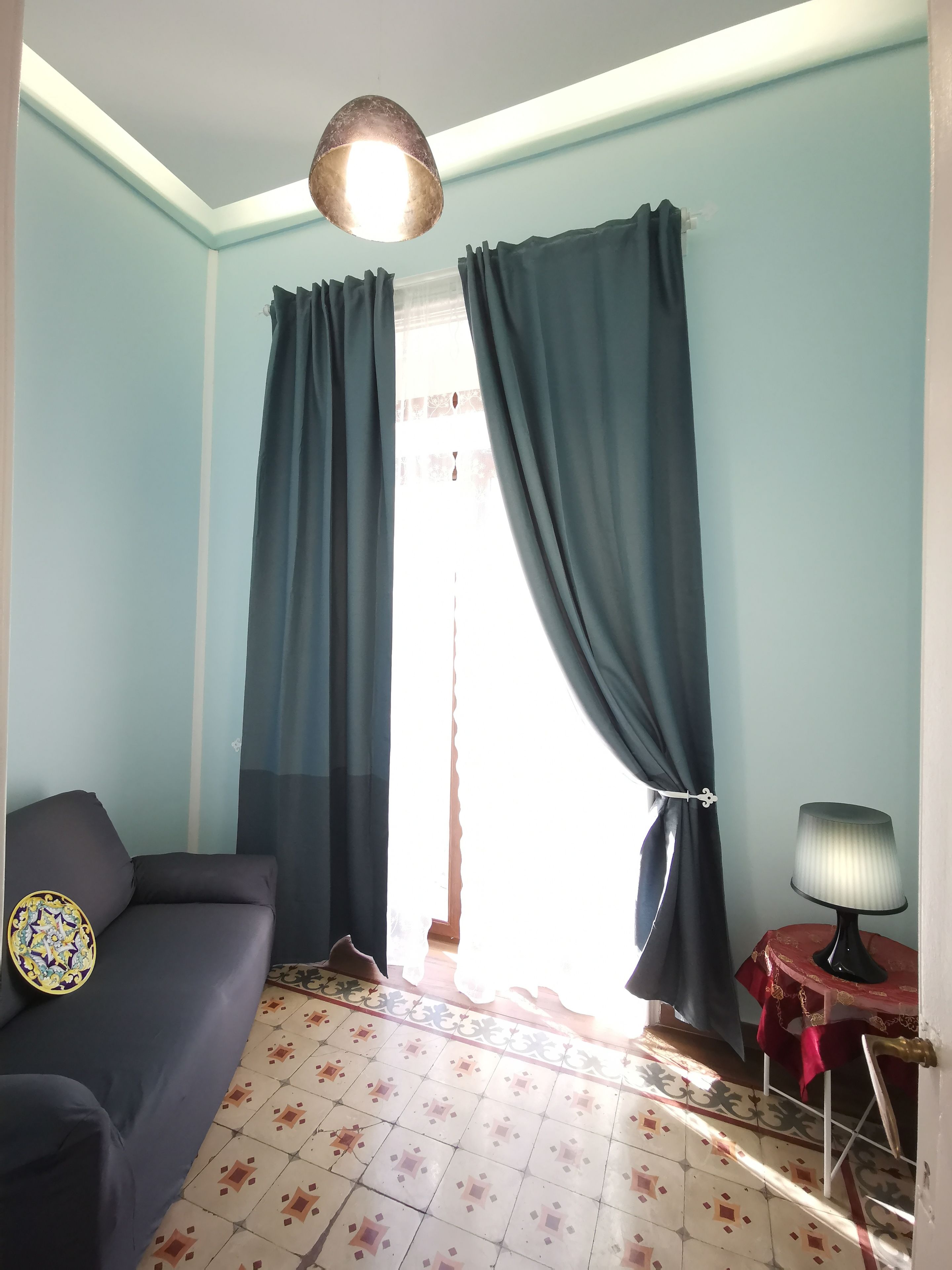 Een kamer met een bank, een lamp en een vloer met een patroon.