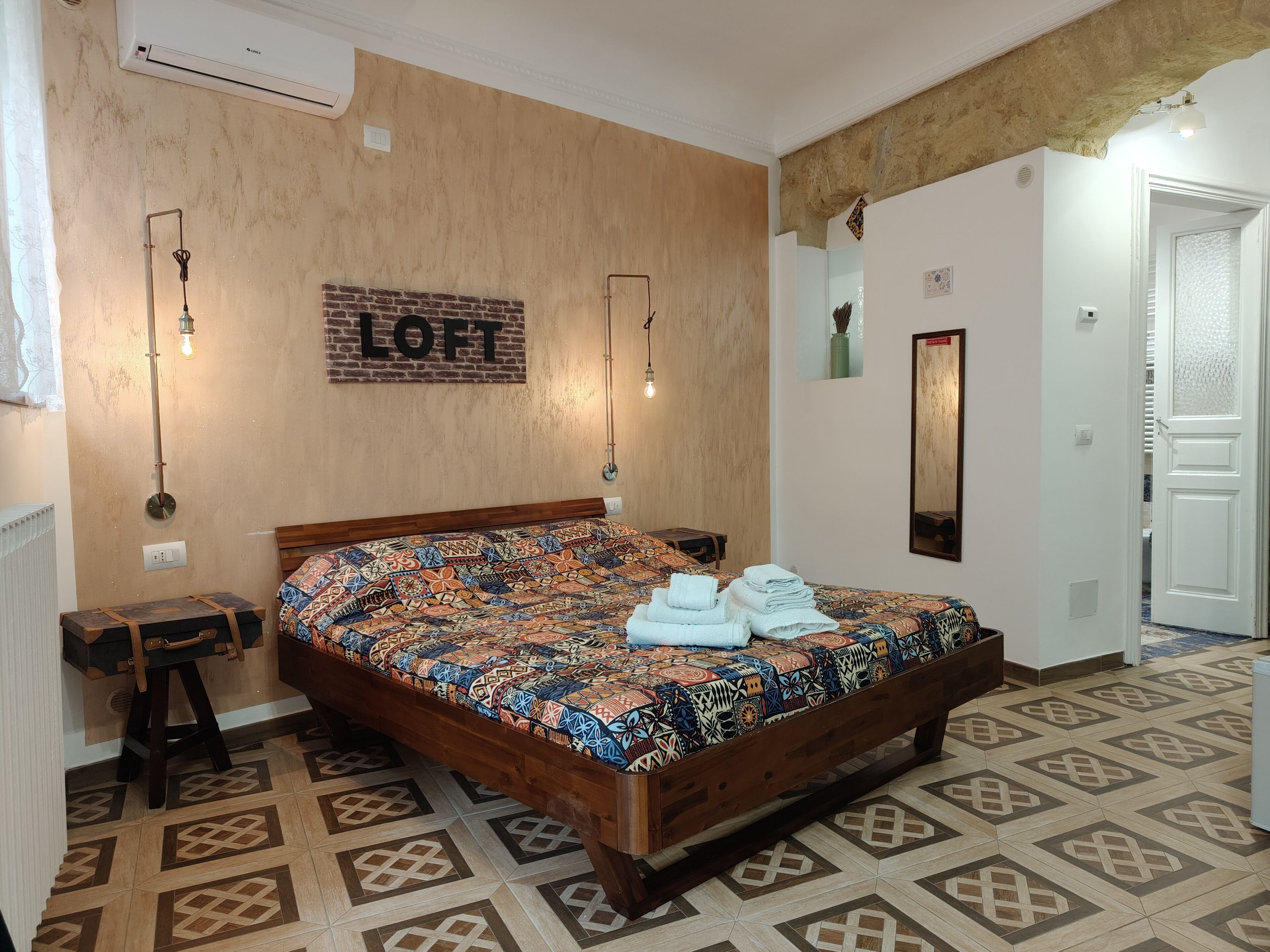 Un dormitorio con una colcha estampada, un cabecero de madera y un letrero en la pared que dice 'LOFT'.