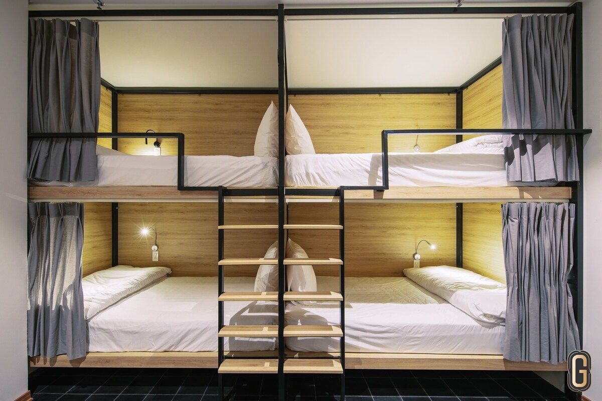 A bunk bed room with a wooden headboard, a ladder, and a small table.