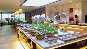A restaurant with a long counter displaying various dishes and bowls, a modern ceiling design, and a staff member at the counter. - The Glomad Boutique Danang by DS (Da Nang)
