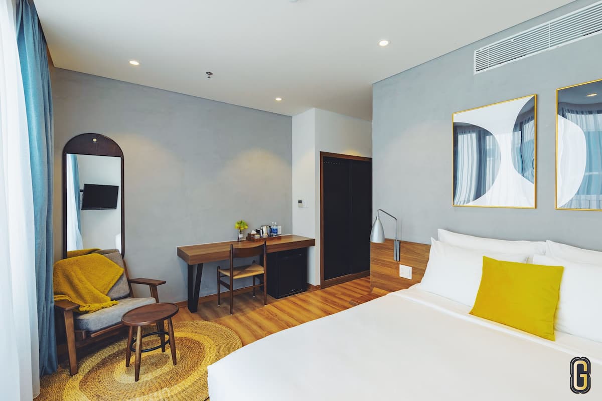 Een hotelkamer met een bed, een bureau, een stoel, een spiegel en een klein tafeltje.