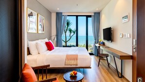 A hotel room with a bed, a desk, a TV, and a view of the sea. - The Glomad Boutique Danang by DS (Da Nang)