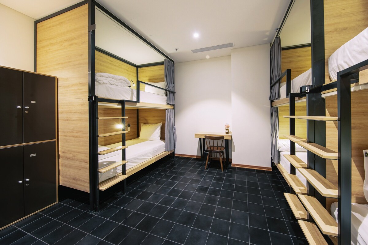 A compact hotel room with bunk beds, a desk, and a wardrobe.