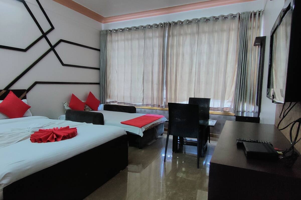 A hotel room with a large bed, a desk, a chair, and a television.