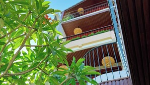 A multi-story building with balconies, surrounded by lush greenery. - Anriva Hoi An (Da Nang)