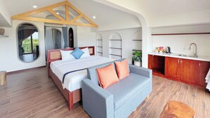 A bedroom with a bed, a sofa, a large window, a kitchen area, and a view of the outdoors. - Anriva Hoi An (Da Nang)