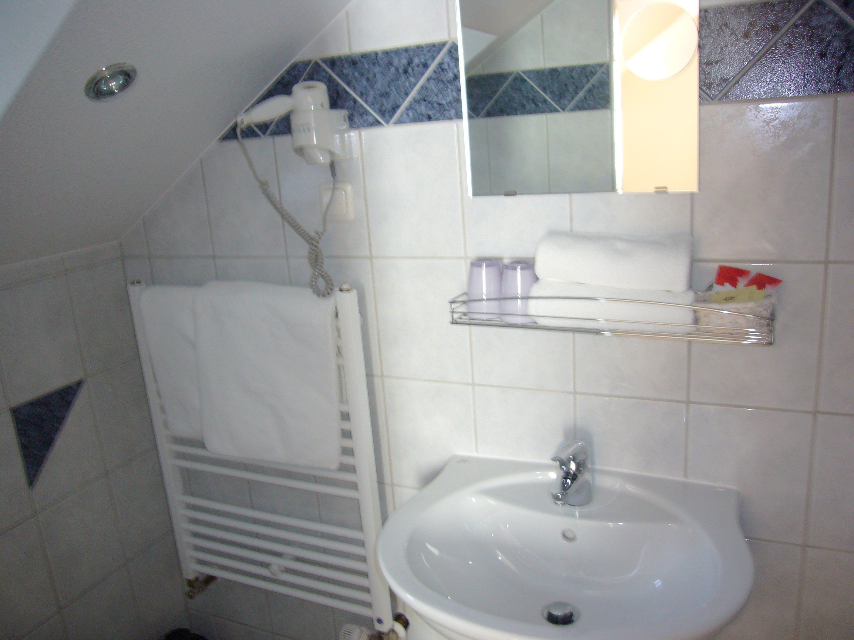 Un baño con lavamanos blanco, toallero y espejo.